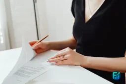 Woman reviewing paperwork at a white desk, a first step in how to apply for SNAP benefits
