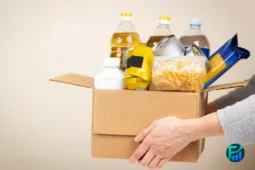 Person holding a cardboard box filled with essential groceries, illustrating a helpful step for those researching how to find a food pantry.