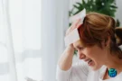 Frustrated woman pressing crumpled bills to her forehead, a moment when a LIHEAP application may help